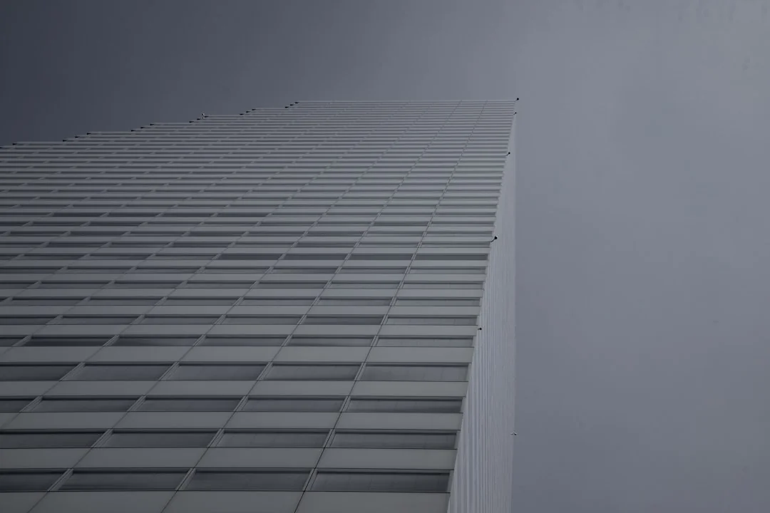 projet-01-d A worker suspended by a harness is washing windows on a tall skyscraper, highlighting the nature of urban high-rise labor.